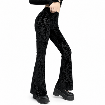 Black velvet flare pants with a dark floral brocade pattern, shown on a model wearing black platform shoes against a white background.