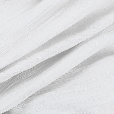A close-up of white textured fabric with a subtle woven or embossed pattern, arranged in soft diagonal folds.