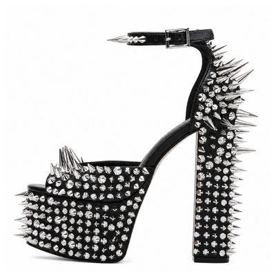 A single black platform sandal with a high block heel, covered in silver spikes and rhinestones, shown from a side profile on a white background.